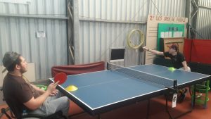 Dois participantes do Programa de Habilidades em Cadeira de Rodas jogando tênis de mesa.