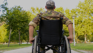Pessoa com deficiência com uma roupa de guerra em um parque numa visão de trás.