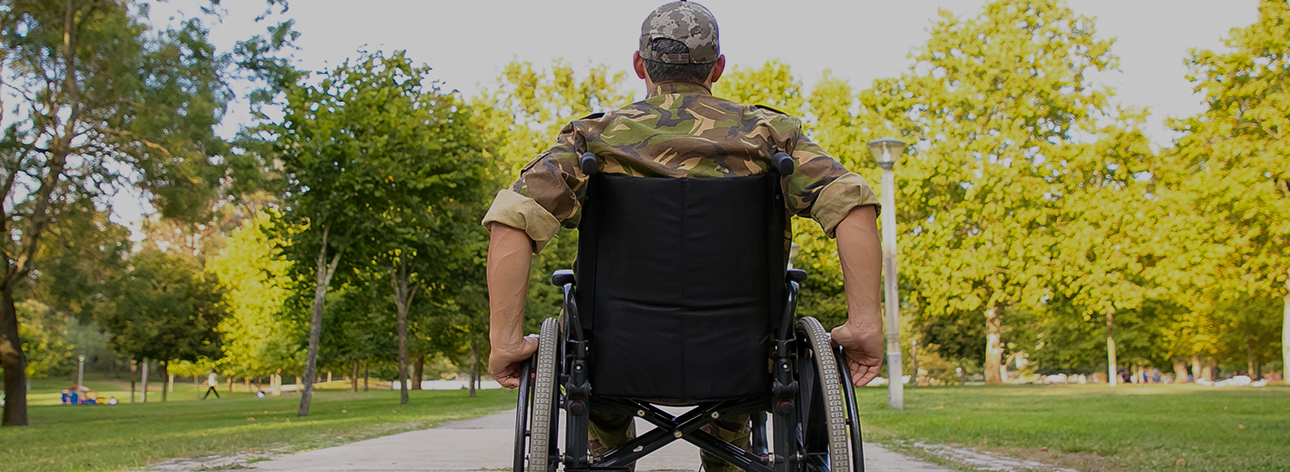 Pessoa com deficiência com uma roupa de guerra em um parque numa visão de trás.